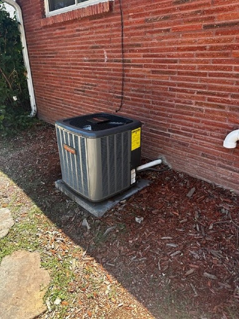 New Amana AC condenser installed in a side yard next to a home with lap siding.