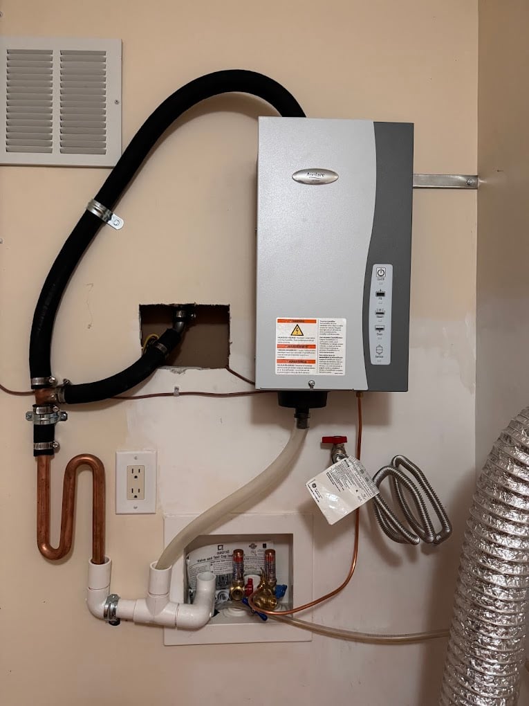 Wall-mounted Aprilaire whole-home humidifier installed with clean copper feed and PVC drain routing.