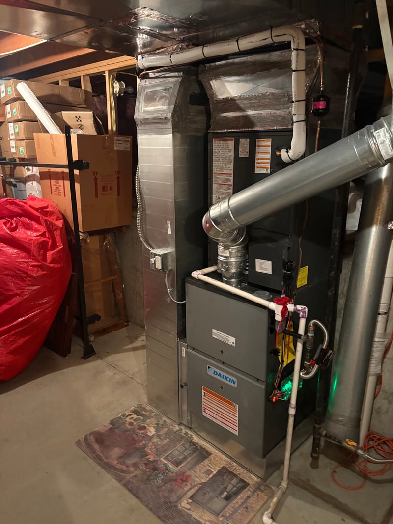 Daikin high-efficiency gas furnace installed in a basement with a new galvanized B-vent flue and PVC intake.
