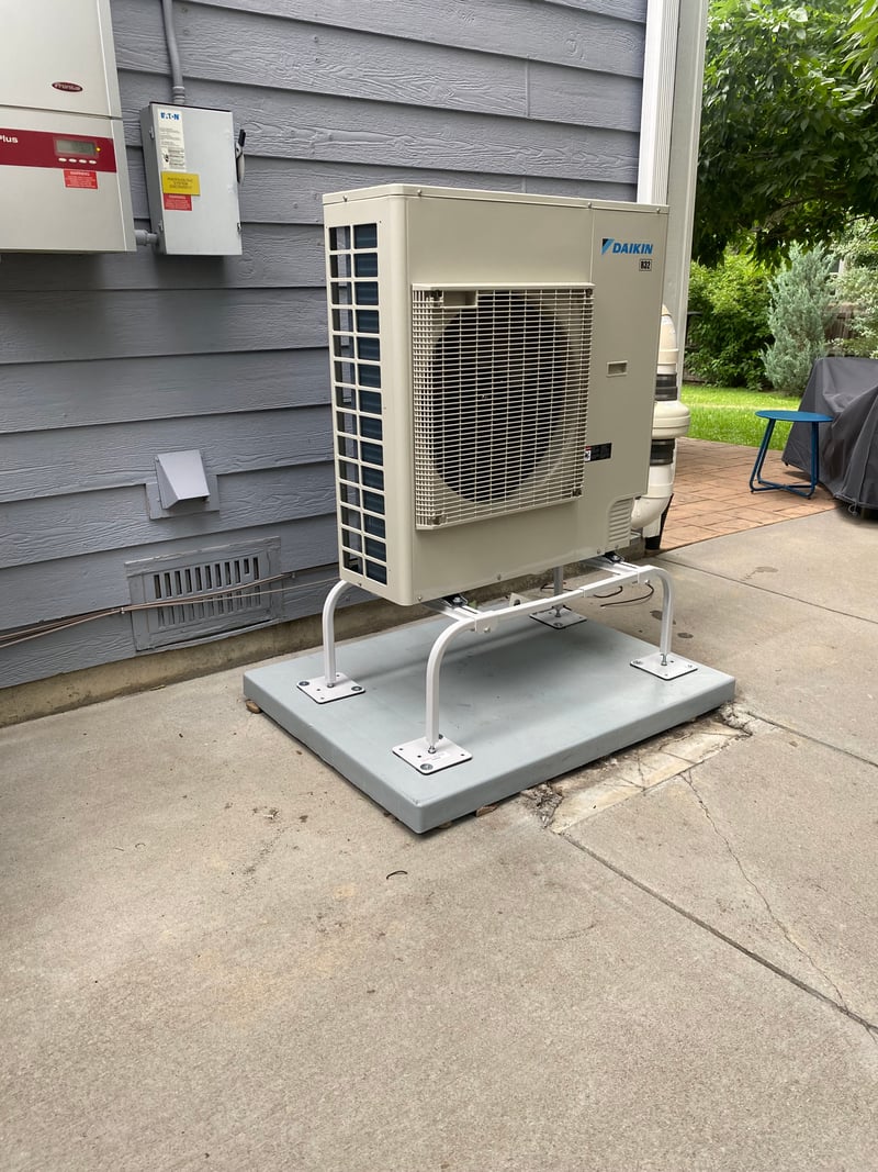 Whole-home Daikin heat-pump conversion mounted on a back-yard concrete slab beside the home.
