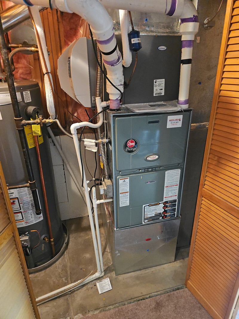 Rheem Prestige furnace and water heater installed side-by-side in a residential utility closet.