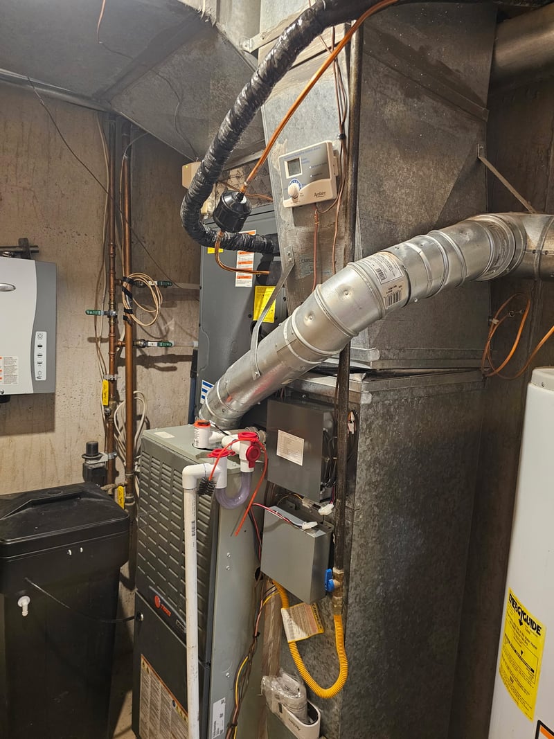 Trane HVAC package installed in a basement mechanical room with insulated refrigerant line-set and Aprilaire humidifier.